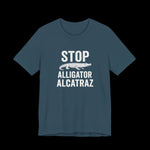 Dark teal t-shirt with white  text and alligator graphic that says "Stop Alligator Alcatraz" on a black background