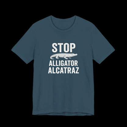 Dark teal t-shirt with white  text and alligator graphic that says "Stop Alligator Alcatraz" on a black background