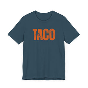 Teal t-shirt with 'TACO' (aka Trump always chickens out) printed in orange on a black background
