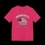 Pink t-shirt with American flag graphic and text that says "Immigrants are what make America Great" on a black background