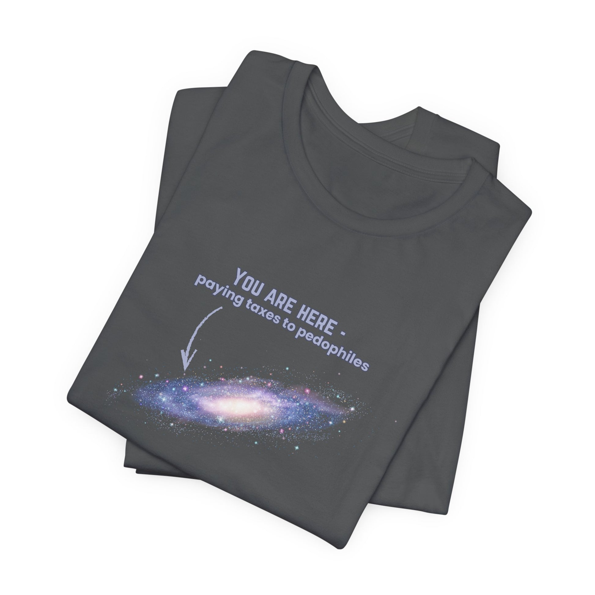 Folded gray t-shirt with graphic of the Milky Way galaxy with an arrow pointing to it and text that says "YOU ARE HERE - Paying taxes to pedophiles" by empowHER by Heidi