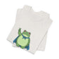 Folded heather cement t-shirt with a bold graphic of the Portland protest frog—red eyes, blue cape, and unimpressed face by empowHERbyHeidi