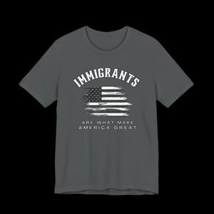 Gray t-shirt with American flag graphic and text that says "Immigrants are what make America Great" on a black background