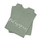 Folded sage green t-shirt with the mathematical equation "8+6+4+7=25" written in chalk like text by empowHER by Heidi