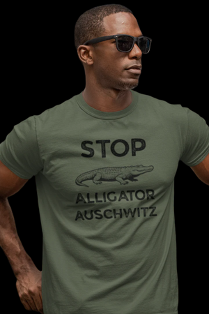 Man wearing a green t-shirt with text that says "STOP ALLIGATOR AUSCHW*TZ" with alligator graphic on a black background